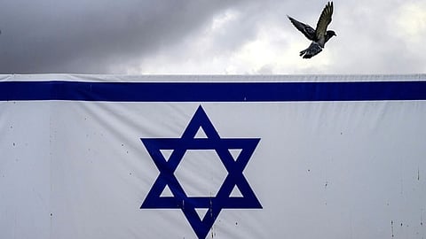 (FILES) A pigeon flies past a giant banner featuring an Israeli flag outside the old city's Jaffa Gate in Jerusalem on 14 November 2023.