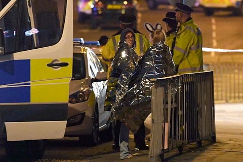 (FILES) Concert goers wait to be picked up at the scene of a suspected terrorist attack during a pop concert by US star Ariana Grande in Manchester, northwest England on 23 May 2017. The man behind a terror attack at a pop concert in Manchester late Monday died when he detonated his device, killing 22 others including children and injuring 59 people, police said on 23 May.
