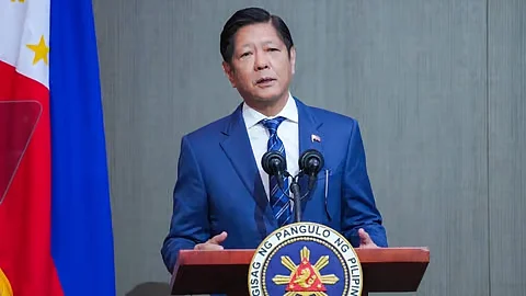 President Marcos on a podium speaking and wearing a blue coat and tie