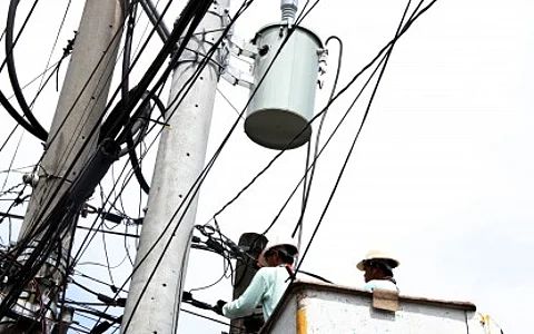 2 Men with a hardhat fixing something on a electric pole