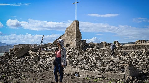 Laid bare A woman takes the opportunity to take a picture with the ruins of a church in the old sunken community of Pantabangan in Nueva Ecija on Friday. The dry spell has caused the dam’s water to recede, laying bare the old enclave.