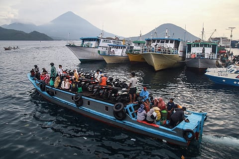 People travel on a wooden boat with motor scooters to Tidore Island ahead of Eid al-Fitr, which marks the end of the Muslim fasting month of Ramadan, at Bastiong port in Ternate, North Maluku, on 7 April 2024.
