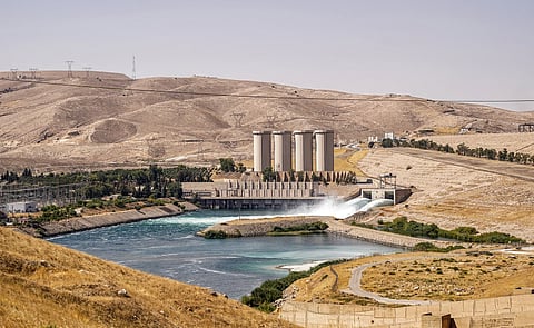 (FILES) This picture taken at the Mosul Dam during a press tour organized by the facility's administration, northwest of Iraq's northern city of Mosul on 21 September 2023, shows a view of the sluice gates emptying water into the Tigris River and the dam's hydroelectric power station.