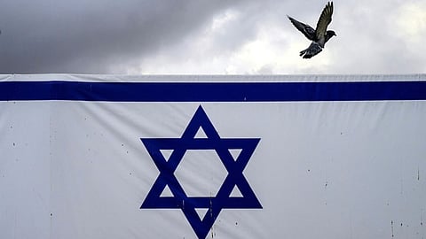 (FILES) A pigeon flies past a giant banner featuring an Israeli flag outside the old city's Jaffa Gate in Jerusalem on 14 November 2023.