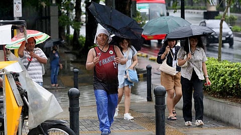 Pedestrians walk fast with their umbrellas