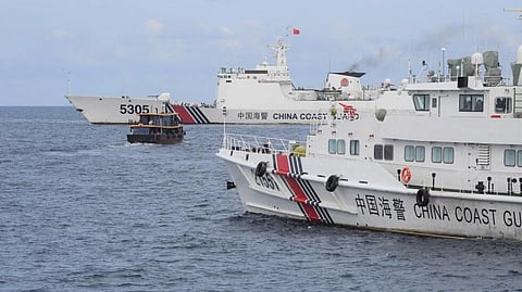 (FILES) Chinese coast guard ships (L and R) corralling a Philippine civilian boat chartered by the Philippine navy to deliver supplies to Philippine navy ship BRP Sierra Madre in the disputed South China Sea, on August 22, 2023.