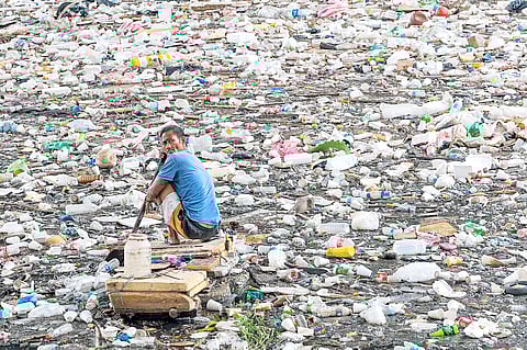 man collects recyclables in San Juan River to junk shops to sell. Plastic bottles and other non-biodegradable materials are repurposed through recycling that helps declog waterways to avoid flooding.