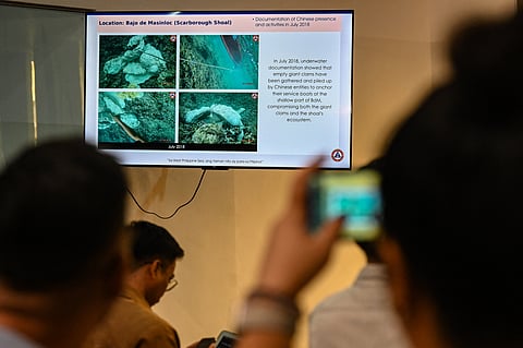 Proof of trespass A journalist takes a photo of a slideshow of the Philippine Coast Guard at its headquarters on Monday, showing continuing Chinese activities in the Scarborough Shoal, part of the Philippines’ exclusive economic zone in the WPS.