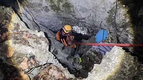 A rescuer slowly navigates a deep chasm in the cave where a busyador, or bird's nest gatherer, fell to his death on Tapiutan Island, El Nido, Palawan.