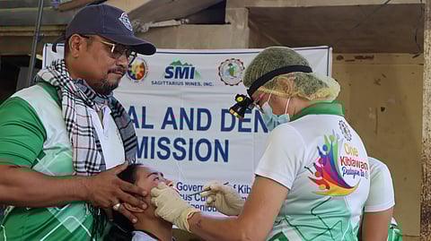 VOLUNTEER dentists examine a patient during the medical mission.