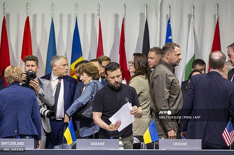 Ukraine's President Volodymyr Zelensky (C) looks at papers as he attends a plenary session at the Summit on peace in Ukraine, at the luxury Burgenstock resort, near Lucerne, on June 16, 2024. The two-day gathering brings together Ukrainian President and more than 50 other heads of state and government, to try to work out a way towards a peace process for Ukraine -- albeit without Russia.