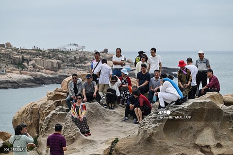 Tourists pose for photos as they visit a scenic spot in front of the sea named 68 nautical miles, in Pingtan island, the closest point in China to Taiwan’s main island, in Fujian province on May 18, 2024.