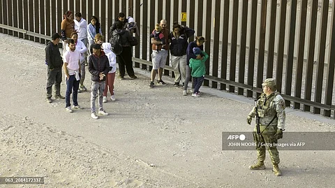 In an aerial view, a Texas National Guard soldier watches over immigrants after they crossed the U.S.-Mexico border to request asylum on March 13, 2024 in El Paso, Texas.