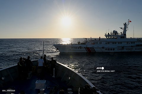 (FILES) This photo taken on March 5, 2024 shows journalists filming as a China Coast Guard vessel (R) sails in front of the BRP Sindangan during a supply mission to Second Thomas Shoal in the disputed South China Sea.