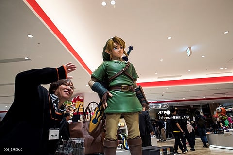 A man poses next to the Link, a game character for Nintendo's "The Legend of Zelda", at a new Nintendo store during a press preview in Tokyo on November 19, 2019.