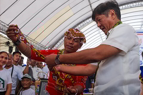 PRESIDENT Ferdinand Marcos Jr. looks at indigenous clothing during the distribution of assistance to families in Surigao del Sur Friday.