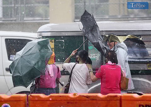 (FILE PHOTO) Commuters hold on tight to their umbrellas due to strong winds brought Habagat and Typhoon Carina along Commonwealth Avenue in Quezon City on 22 July, 2024