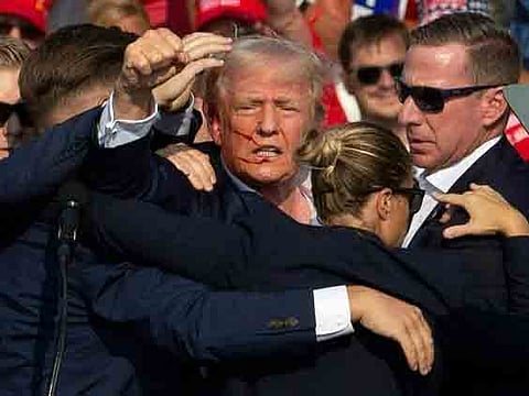 Donald Trump gestures as he is surrounded by US Secret Service agents