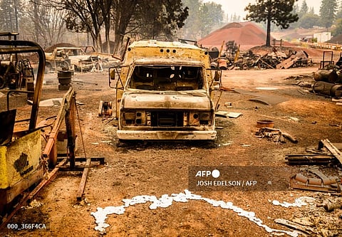 A burned vehicle smolders in the Paynes Creek area of unincorporated Tehama County, California, during the Park fire on July 27, 2024. The fast-moving and rapidly growing wildfire has forced more than 4,000 people to evacuate as firefighters battle gusty winds and perilously dry conditions, authorities said on July 26, 2024. An arsonist is suspected to have started the fire which has burned more than 340,000 acres and burned dozens of homes.