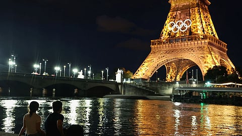 Spectators view the Eiffel Tower and Olympic rings along the Seine river.