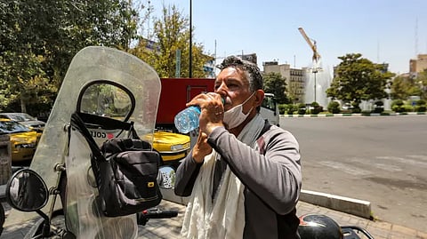 A motorcyclist has a drink from a bottle to cool off during a heat wave