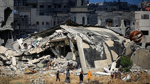 Palestinian women and boys walk towards destroyed buildings, as some residents return to the city of Khan Yunis, in the southern Gaza Strip on 30 June 2024.