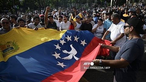 Demonstrators wave a big Venezuelan flag during a protest against Venezuelan President Nicolas Maduro's government in Caracas on July 29, 2024, a day after the Venezuelan presidential election. Protests erupted in parts of Caracas Monday against the re-election victory claimed by Venezuelan President Nicolas Maduro but disputed by the opposition and questioned internationally, AFP journalists observed.