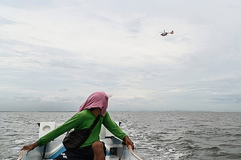 Eyes in the sky A fisherman watches a chopper of the Philippine Coast Guard surveying the oil spill from a tanker that capsized off Manila Bay near Bataan last week. The tanker was carrying 1.4 million liters of industrial oil.