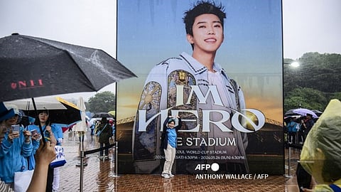 (FILES) This photo taken on 26 May 2024 shows a fan posing for photos with a poster of trot singer Lim Young-woong before attending his 'IM HERO - THE STADIUM' concert at the Seoul World Cup Stadium in Seoul. Lim Young-woong may not have as many fans as BTS, but the trot singer is rivaling the global superstars, showing there's more to South Korean music than K-pop with his billions of streams and a sold-out stadium tour.