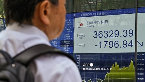 (FILE PHOTO) A man looks at a display board showing the morning numbers on the Tokyo Stock Exchange along a street in Tokyo on August 2, 2024. Tokyo stocks fell more than five percent on August 2 after Wall Street shares tumbled over concerns about the US economy.