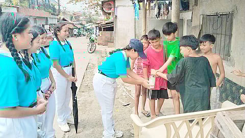 CHILDREN put cash into a coin bank during a donation drive by Tzu Chi scholars in the Pulpogan neighborhood of Cebu.