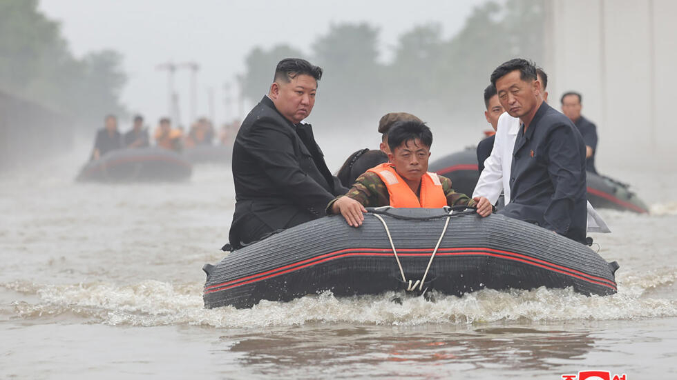 An undated photo released by North Korea's official Korean Central News Agency shows leader Kim Jong Un (left) in a dinghy as he inspects a floot-hit part of Sinuiju