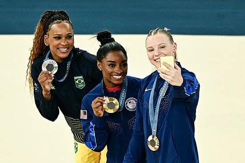 SIMONE Biles of the United States (middle) takes a selfie with Rebeca Andrade of Brazil (left) and Jude Carey of the United States during the awarding ceremony of the women’s floor exercise event of the Paris Olympics.