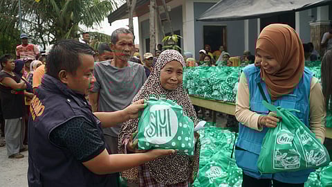 STAFF of the Municipal Disaster Risk Reduction and Management Office hands food packs donated by BDO Foundation to residents of Barangay Kabuntalan in Maguindanao del Norte.