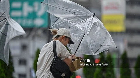 LOOK: A woman tries to hold on to her umbrella in the wind and rain outside Shinjuku Station in central Tokyo on 16 August 2024, as Typhoon Ampil approaches the Japanese capital. The "very strong" typhoon buffeted Japan's Pacific coast with fierce winds and heavy rain, forcing the cancellation of hundreds of flights and trains in the Tokyo area and leaving over 2,000 homes without power.