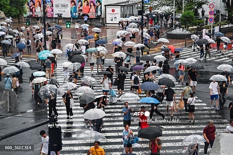 Pedestrians use their umbrellas to shelter from the rain while walking across Shibuya Crossing in central Tokyo on August 16, 2024, as Typhoon Ampil approaches the Japanese capital. The "very strong" typhoon buffeted Japan's Pacific coast with fierce winds and heavy rain on August 16, forcing the cancellation of hundreds of flights and trains in the Tokyo area and leaving over 2,000 homes without power.