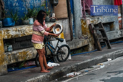 A woman tries to clean burnt rice on Sunday to ensure that her family can still make use of it. The Philippine Statistics Authority (PSA) reported that a Filipino family of five needs nearly P14,000 per month to meet basic food and non-food needs, with the poverty threshold varying by region. PHOTO BY YUMMIE DINGDING