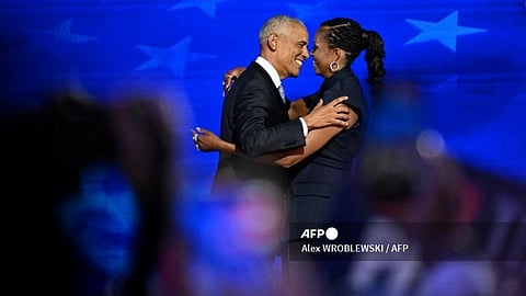 Former US President Barack Obama (L) hugs wife Former US First Lady Michelle Obama as he arrives on stage to speak on the second day of the Democratic National Convention (DNC) at the United Center in Chicago, Illinois, on 20 August 2024. Vice President Kamala Harris will formally accept the party’s nomination for president at the DNC which runs from 19-22 August in Chicago.
