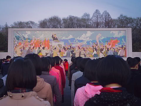 CHILDREN line up in front of a mural in Pyongyang, North Korea.