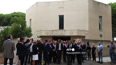 France's Prime Minister, Gabriel Attal (L) flanked by France's Minister for the Interior and Overseas, Gerald Darmanin (C), and French MPs exit the synagogue which was set on fire and where an explosion of cars occurred in La Grande-Motte, south of France, on 24 August 2024. At least two cars, one containing a gas bottle, were set alight on the morning of 24 August 2024, in front of the synagogue in La Grande-Motte, causing an explosion that injured a local policeman, the French gendarmerie and the town's mayor said.