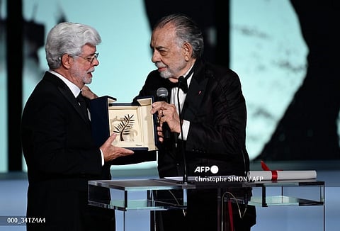 US director George Lucas (L) receives the Honorary Palme d’Or from US director Francis Ford Coppola during the Closing Ceremony at the 77th edition of the Cannes Film Festival in Cannes, southern France, on May 25, 2024.