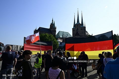 Supporters hold up giant German national flags in front of the Cathedral in Erfurt, eastern Germany on 31 August, 2024, during the last campaign event of the far-right Alternative for Germany party (AfD) for the upcoming Thuringia state elections. The former East German states of Saxony and Thuringia prepare to hold key regional elections on 1 September, 2024.