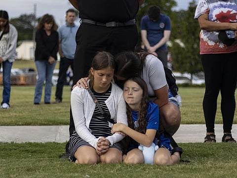 A mother and her children bow their heads in prayer at a vigil for the victims of the Apalachee High School shooting in Winder, Georgia