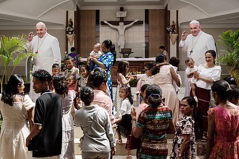 Catholic faithful take pictures with installed two life-size boards of Pope Francis after a Sunday mass at the Church of Saint Anthony of Motael ahead of Pope Francis’ visit in Dili on September 8, 2024.