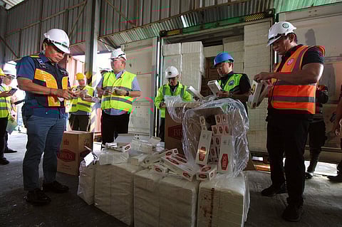 Agriculture Secretary Francisco Tiu Laurel and BOC Port of Subic Atty. Ricardo Uy Morales II inspect the smuggled contraband presented to the media on Wednesday at the New Container Terminal. The P136 million of smuggled items that were found inside seven container vans include fake cigarettes and vegetables that came from Taiwan and China, respectively.