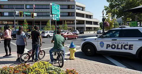 People watch as Springfield Police Department officers investigate the Springfield City Hall after bomb threats