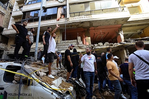 People gather in front of a building targeted by an Israeli strike in Beirut's southern suburbs on September 20, 2024. The strike on Hezbollah's stronghold in Lebanon's capital Beirut reportedly killed at least eight people and wounded dozens of others, with a source close to the movement saying a top military leader was dead.