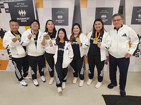 NATIONAL chess team members Mae Mendoza, Bernadette Galas, Janelle Mae Frayna, Jan Jodilyn Fronda and Ruelle Canino smile after winning the gold medal in Category B of the women’s section of the 45th FIDE Chess Olympiad in Budapest, Hungary. Also shown are team captain Jayson Gonzales and men’s squad coach Eugene Torre.