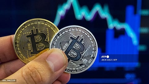 (FILES) A picture taken on 6 February 2018 shows a person holding a visual representation of the digital crypto-currency Bitcoin, at the "Bitcoin Change" shop in the Israeli city of Tel Aviv.