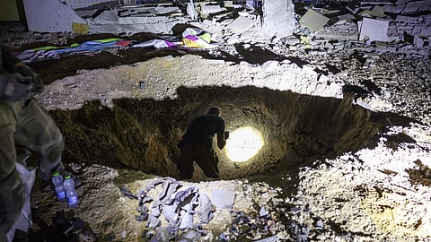 Members of Israel's Home Front Command and police forces inspect a crater left by an exploded projectile at a heavily damaged school building in Israel's southern city of Gedera on 1 October 2024, after Iran launched a barrage of missiles at Israel in response to the killings of Lebanese Hezbollah leader Nasrallah and other Iran-backed militants.